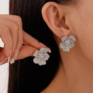 Sparkling silver flower stud earrings with pave set crystals worn by a model