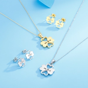 Macro shot of gold and silver four-leaf clover jewelry set with engraved Mae lettering