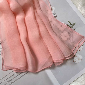 Detail shot of pink silk-feeling scarf texture on a book, showcasing soft polyester fabric
