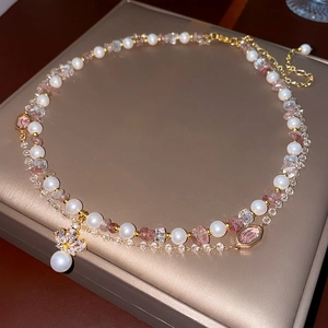 Macro detail of a double-layer crown necklace with white pearls and pink crystal beads