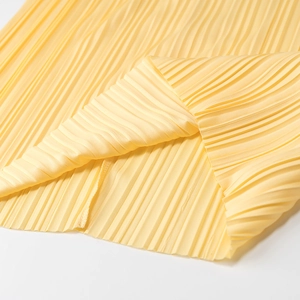 Gros plan de la texture du tissu plissé jaune montrant des plis élégants et légers