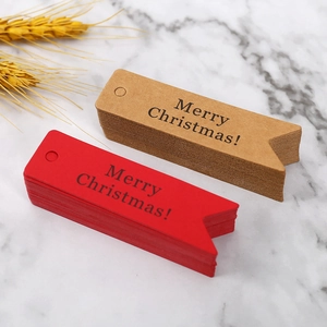 Dettaglio di etichette regalo natalizie in carta rossa e kraft su marmo bianco