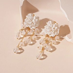 Detail of white acrylic flower earring with gold chain, glass beads and crystals