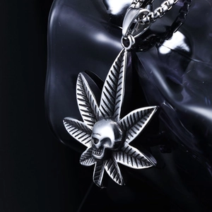 Macro shot of silver stainless steel maple leaf and skull pendant with metallic polish