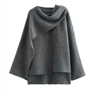Dettaglio ravvicinato del poncho in maglia grigio scuro che mostra la trama del tessuto