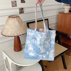 Dettaglio della borsa tote in tela tie-dye blu e bianca con logo laterale e trama del tessuto