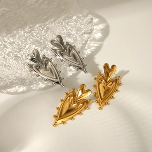 Detailed view of double layered heart stud earrings in polished gold and silver finishes