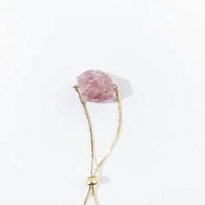 Close-up of raw pink crystal stone on adjustable gold box chain bracelet