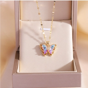 Macro detail of gold-plated butterfly pendant with iridescent colorful crystals in a gift box