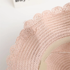 Close-up of pink straw sun hat showing intricate woven texture and scalloped edge detail