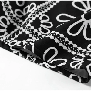 Detailed close-up of white daisy floral print on black fabric with fine stitching