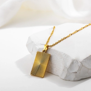 Detail of 18k gold plated rectangular pendant with sunburst texture on white stone