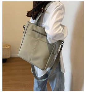 Olive green large canvas tote bag with black metal hardware shown on model's shoulder