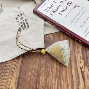 Macro shot of triangle fabric zongzi pendant with vintage jacquard on wooden background