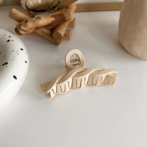 Close-up of a cream beige matte hair claw clip with elegant wave woven texture design