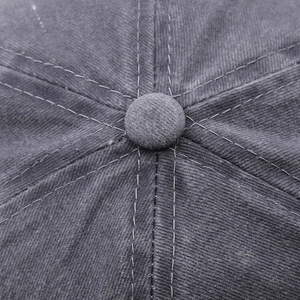 Macro shot of the stitched top button and twill fabric texture on a washed cotton baseball cap