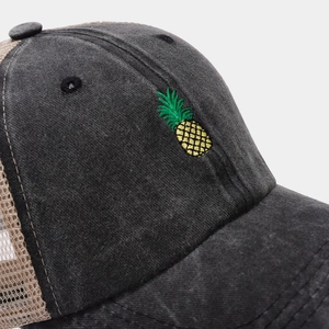 Macro detail of pineapple embroidery on washed grey cotton and beige mesh baseball cap