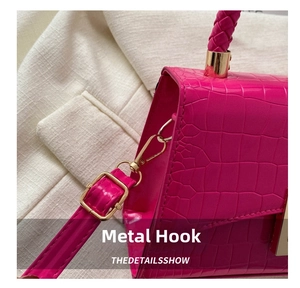 Detail of fuchsia crocodile pattern leather bag with gold hardware and woven handle