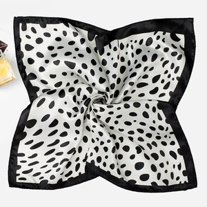 Detail of a square silk scarf with black and white polka dot patterns in a spiral fold