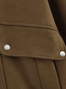 Détail d'une poche de veste en daim camel avec un bouton pression en métal argenté