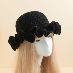 Detail of black handmade crochet knit bucket hat with wavy ruffled brim on model