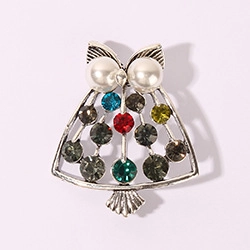 Detailed macro view of an owl brooch with silver metal, pearls, and colorful rhinestones