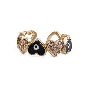 Detail of adjustable gold heart ring featuring black devil eye pattern and white zircons