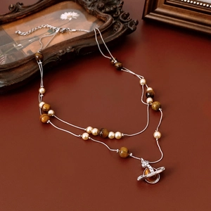 Close-up of double-layer vintage necklace with pearls, tiger eye stones, and Saturn pendant