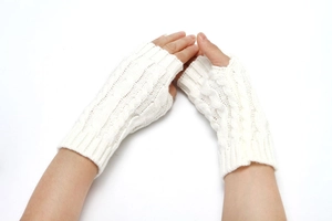 Macro detail of white cable knit fingerless gloves showing texture and thumb hole