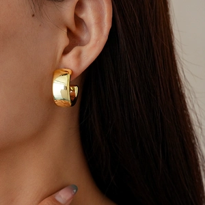 Close-up of model wearing chunky golden C-shape geometric water drop stud earrings