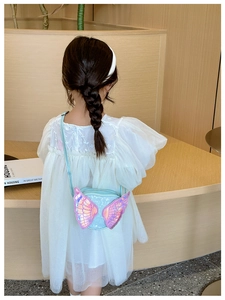Cute blue girls crossbody bag with pink angel wings shown on a child in a room