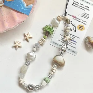 Tropical sea shell beaded phone charm with starfish and coconut tree charms on white background