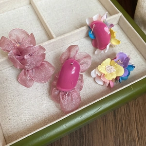 Detail view of handmade chiffon flower earrings in pink and purple on display tray