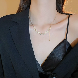 Dettaglio di una collana a fiori placcata oro con perle indossata da una modella
