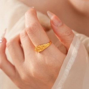 Dettaglio ravvicinato di un anello vintage dorato con motivo floreale a rilievo sul dito
