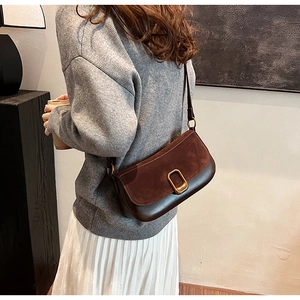 Close-up of suede flap and leather shoulder bag with golden square metal clasp