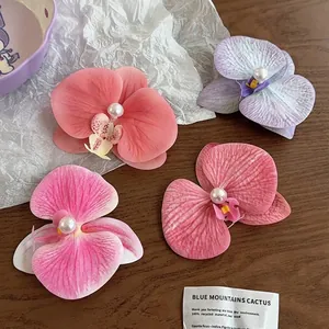 Elegant orchid flower hair clips with pearl centers in four pastel colors on wooden desk
