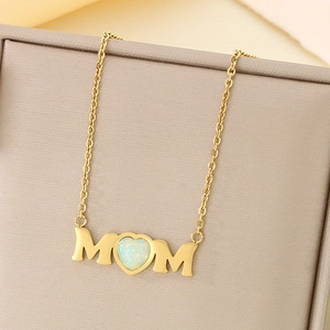 Detail of gold MOM necklace with heart-shaped opal inlay on a jewelry gift box