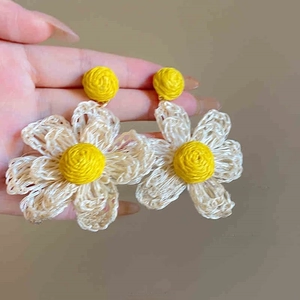 Detail showing white daisy woven earrings with cotton petals and yellow center, size 7.5cm