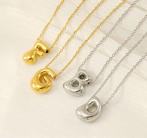Detailed close-up of bubble alphabet pendants in gold and silver on silk fabric