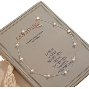 Elegant freshwater pearl necklace on silver chain displayed on a vintage French notebook