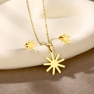 Detailed shot of golden sunburst necklace and earrings set on a white ceramic tray