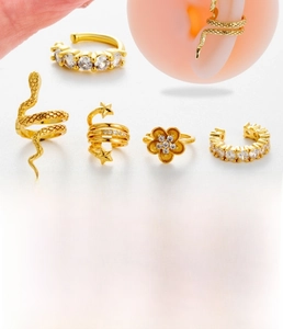 Detail of gold-plated ear cuff set with zircon snakes, flowers and stars on a model ear