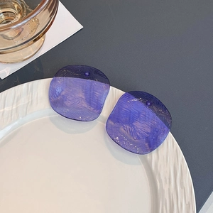 Detail view of purple geometric acrylic earrings with textured finish on a white plate