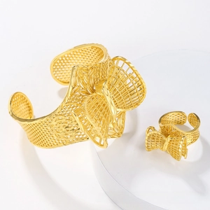 Detailed view of ornate hollow gold bracelet and ring set with elegant 3D bow design