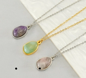 Detailed macro view of natural stone pendants in purple, green, and pink on steel chains