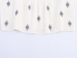 Close-up of navy ethnic geometric embroidery on white linen cotton shirt fabric