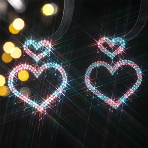 Detail of luxury heart earrings with sparkling pink and blue crystals on black background