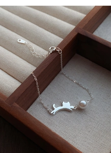 Dettaglio macro del ciondolo a gatto in argento S925 e perla su un bracciale raffinato