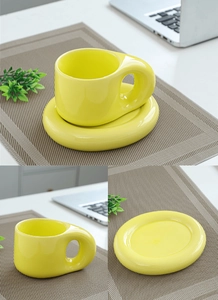 Close-up of yellow ceramic mug and saucer set with a thick handle on a desk